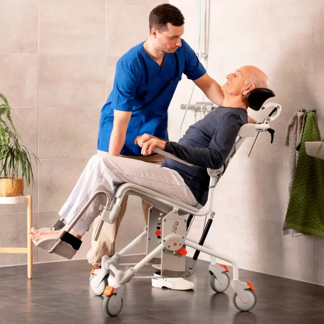 Person using a medical device with a healthcare professional assisting in a bathroom setting.