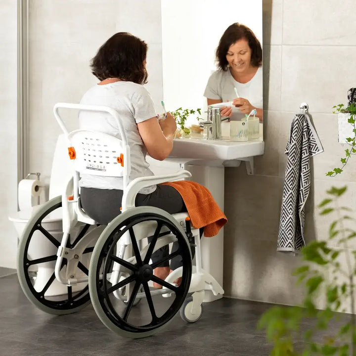 Person using a wheelchair in a bathroom setting, interacting with a sink.