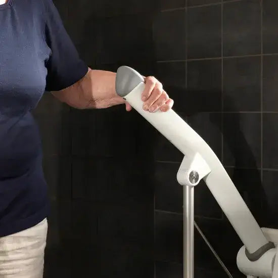 Person using a white and gray grab bar against a black tiled wall.