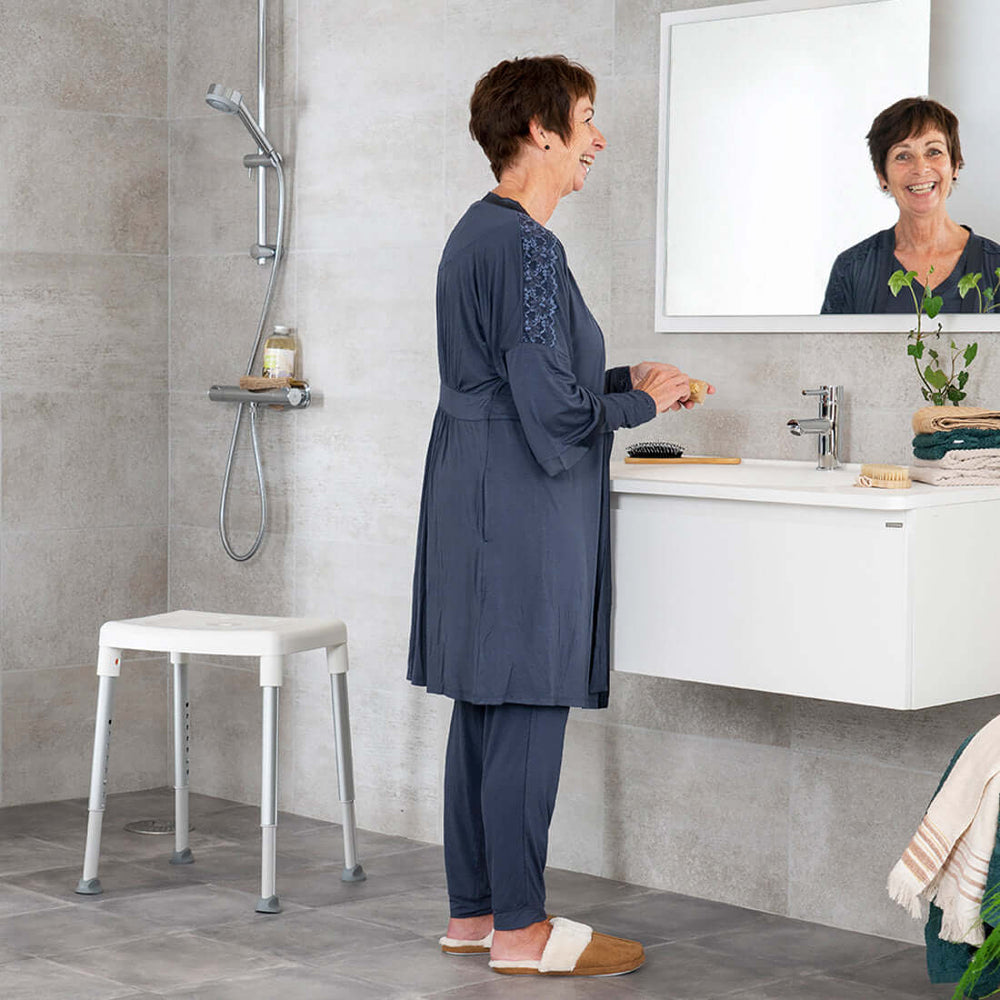 etac smart shower stool on reliable ramps sitting next to woman smiling in the mirror