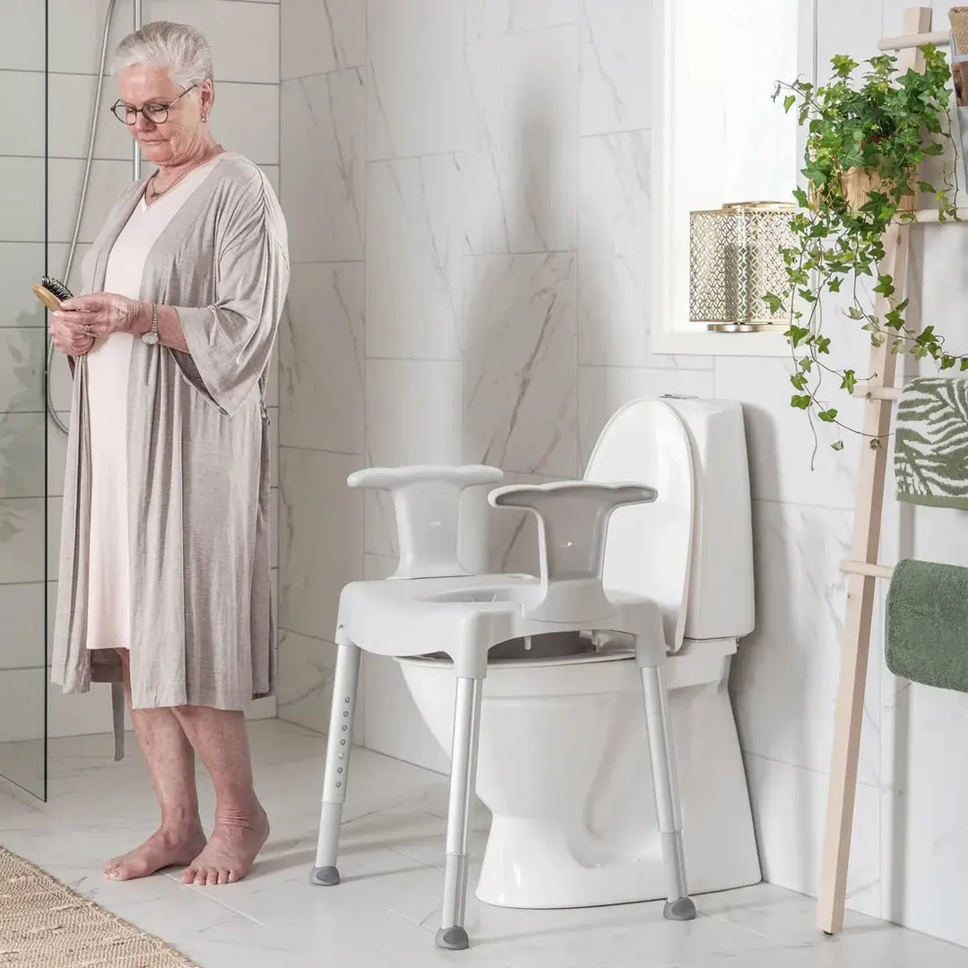 Woman in a bathroom with a toilet seat attachment for elderly or disabled people.