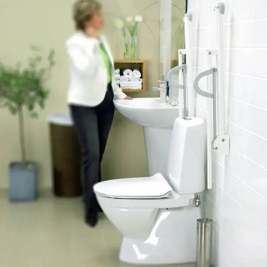 Bathroom with a toilet and sink, blurred figure of a person in the background.