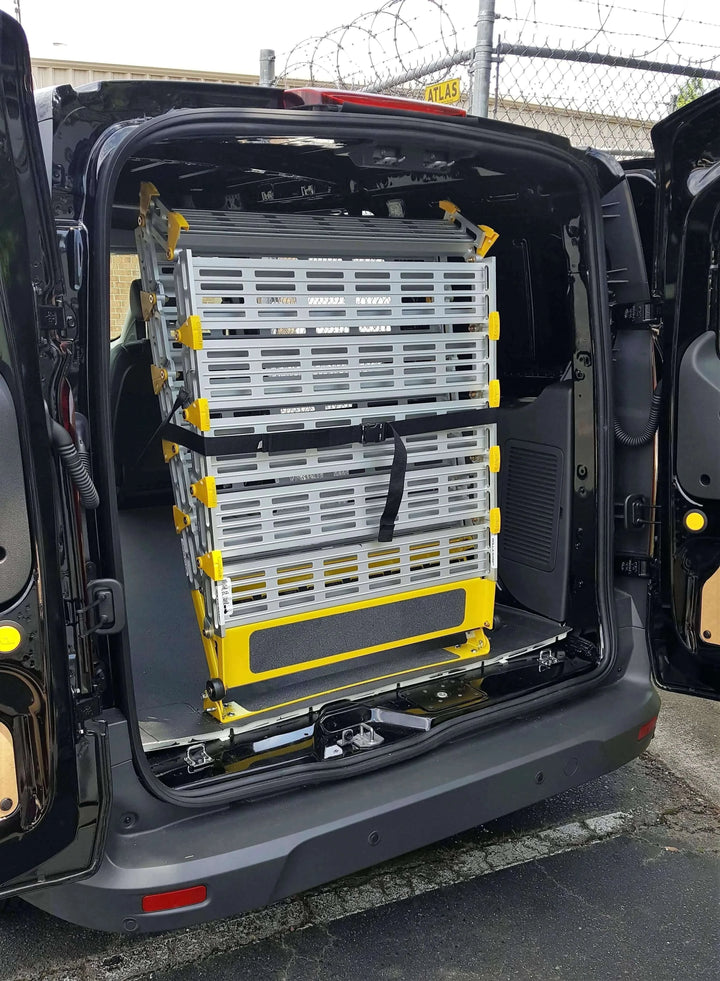 Roll-A-Ramp manual van ramp from Reliable Ramps folded up and strapped down in a black van