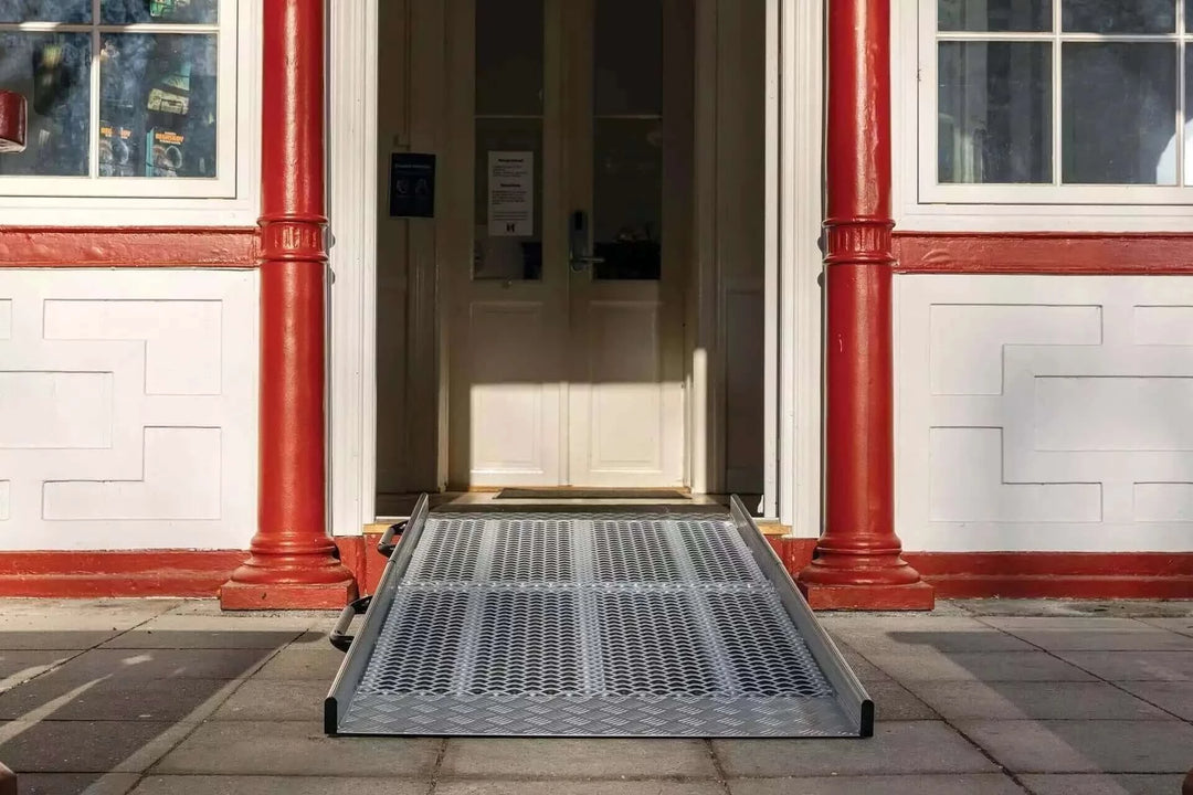 Guldmann - Stepless Wide Folding Pro Portable Wheelchair Ramp used by a patient coming out of a house