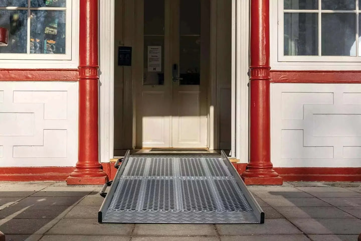 Guldmann - Stepless Wide Folding Pro Portable Wheelchair Ramp used by a patient coming out of a house