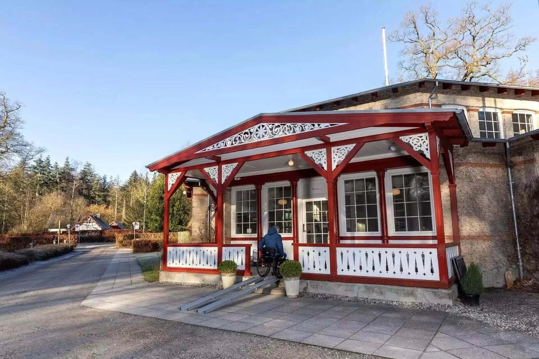 Guldmann - Stepless Folding Telescopic Portable Wheelchair Ramp being used outside by patient coming out of house