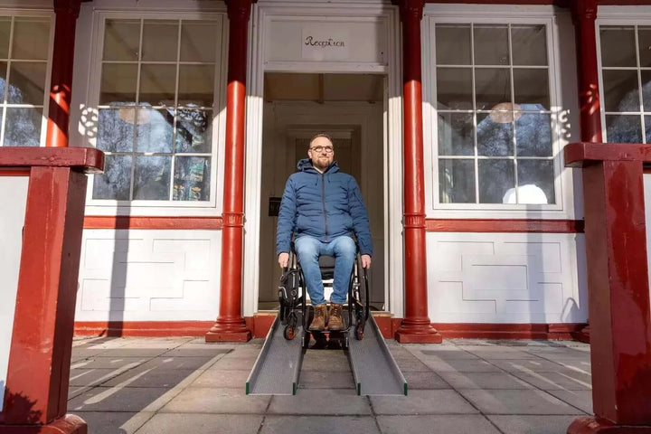 Guldmann - Stepless Telescopic Portable Wheelchair Ramp used by a patient coming out of a house