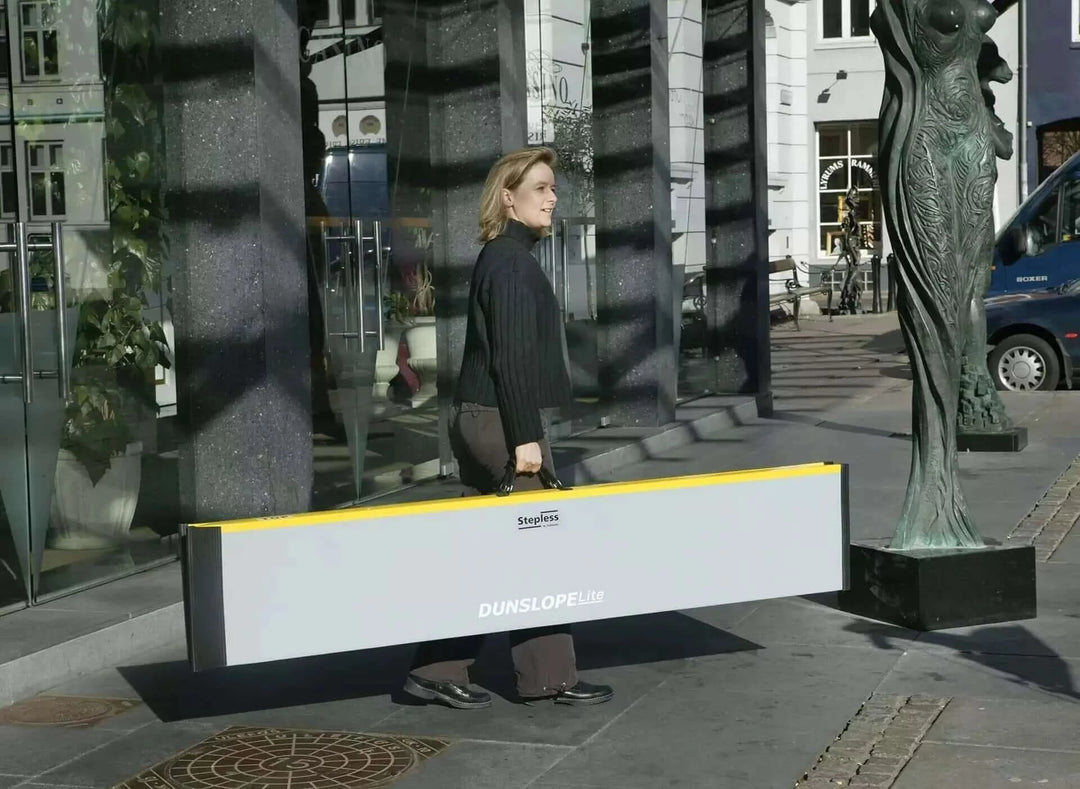 Guldmann - Stepless Single Folding Lite Wheelchair Ramp being held by a user as its folded up
