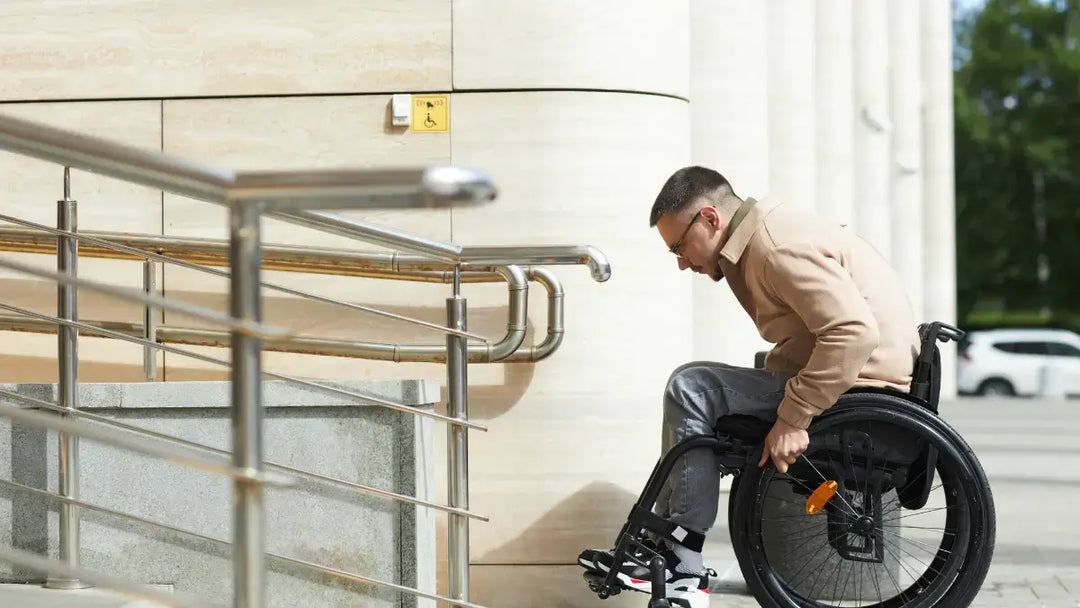 man in a wheelchair about to go up a commercial wheelchair ramp outside