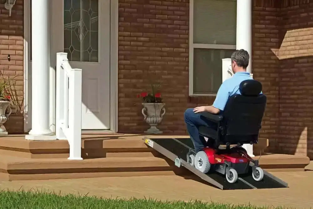 man going up a portable wheelchair ramp in front of a house on a motorized handicap scooter