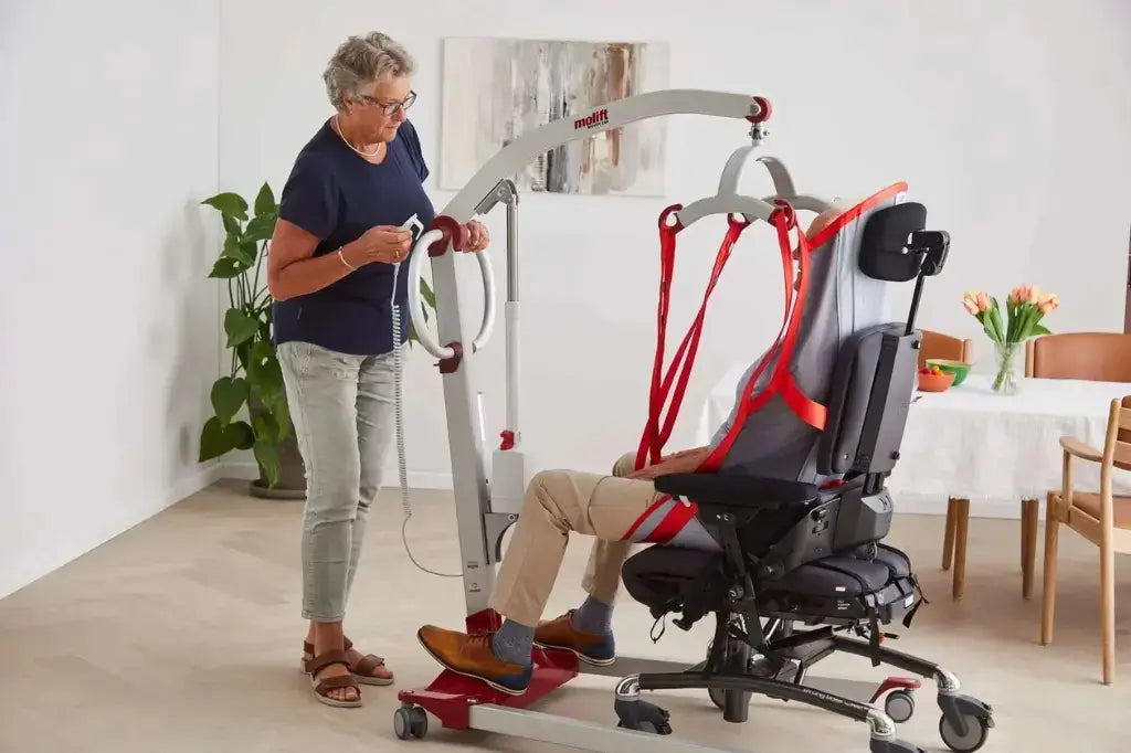 older lady helping man in power chair and using a patient lift