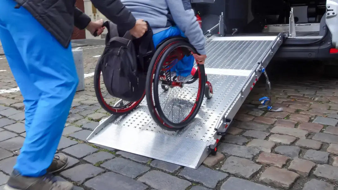 man going up a ramp with his wheelchair being pushed by a helper.