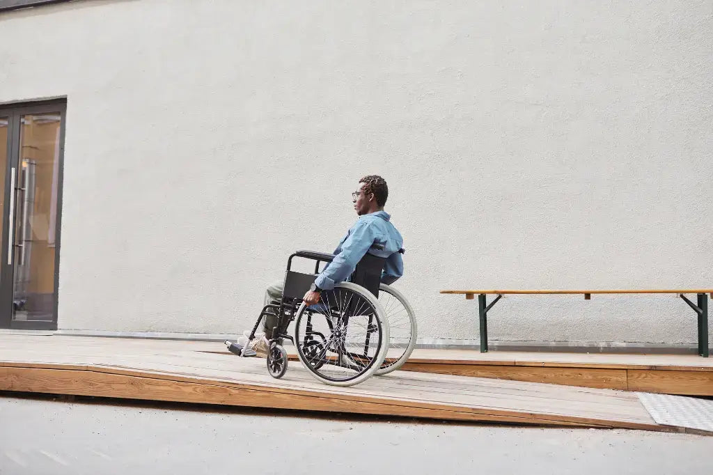 man in blue shirt going up a wooden wheelchair ramp in front of a building