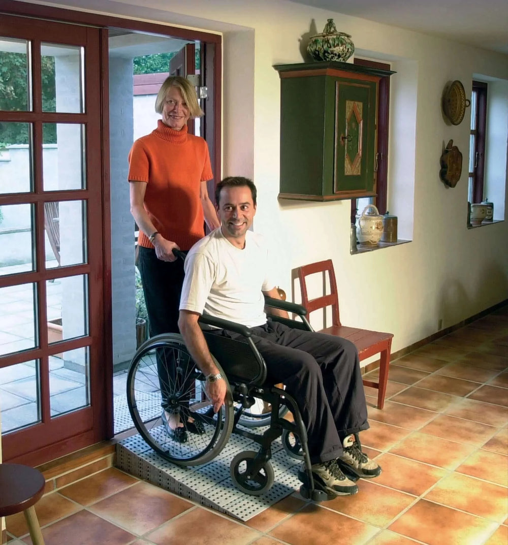 Guldmann - Stepless Excellent Threshold Ramp Kit being used by wheelchair user and caretaker in a home