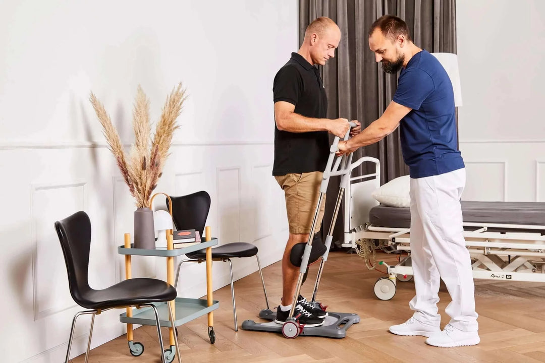 man being helped to stand up out of a chair by a nurse using the molift raiser PRO