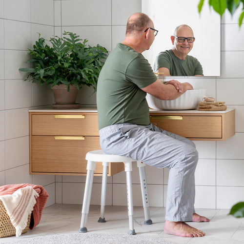 etac easy shower stool from reliable ramps being used by a man at the sink
