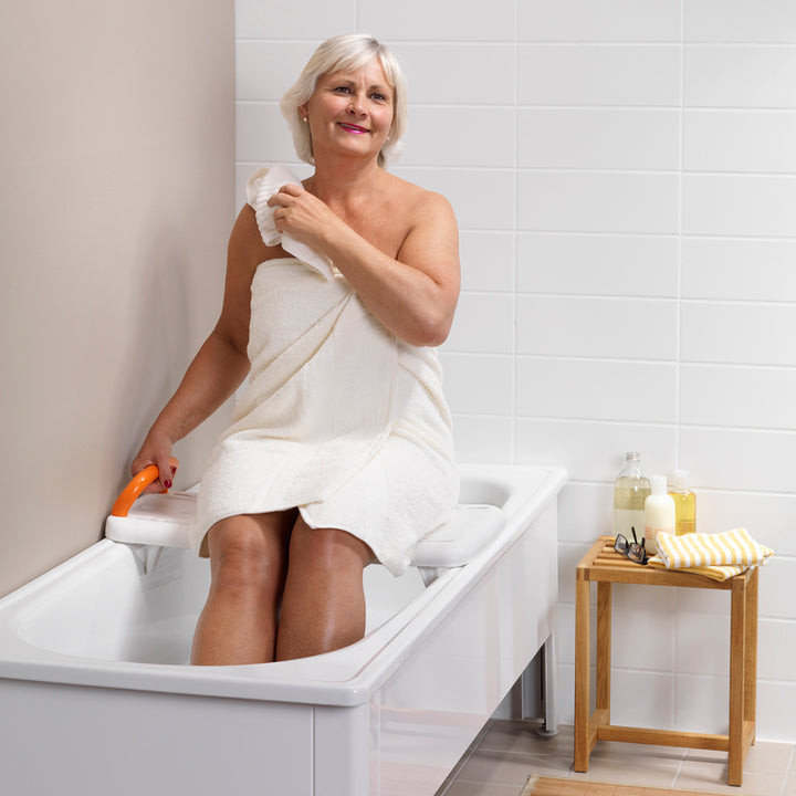 etac fresh bath board from reliable ramps showing lady sitting on it
