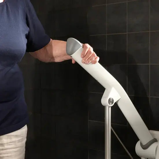 Person using a white and gray grab bar against a black tiled wall.