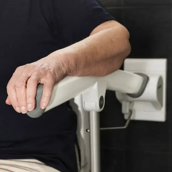 Person using a grab bar in a bathroom setting
