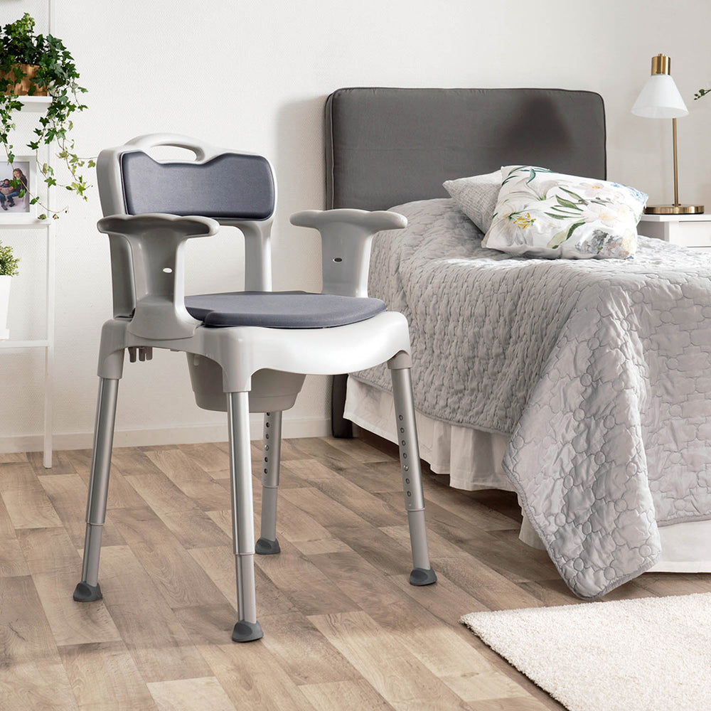 Gray and white chair in a bedroom setting with a bed and nightstands.