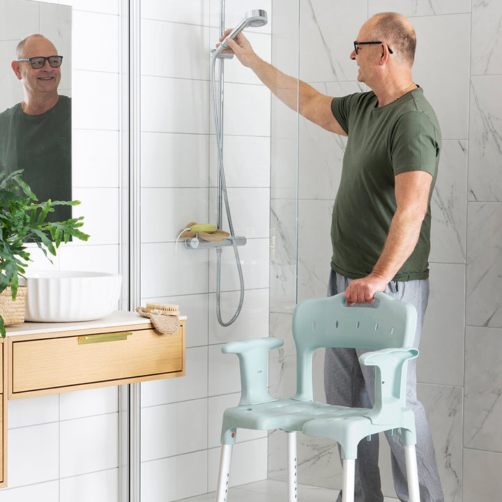etac swift shower stool/chair from reliable ramps being used by man in shower with shirt on