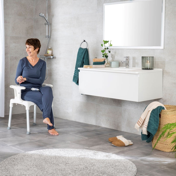 etac swift shower stool/chair from reliable ramps being used by a lady in the bathroom
