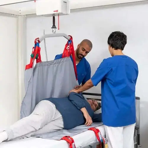 two nurses helping a lady into a body sling and using a ceiling lift
