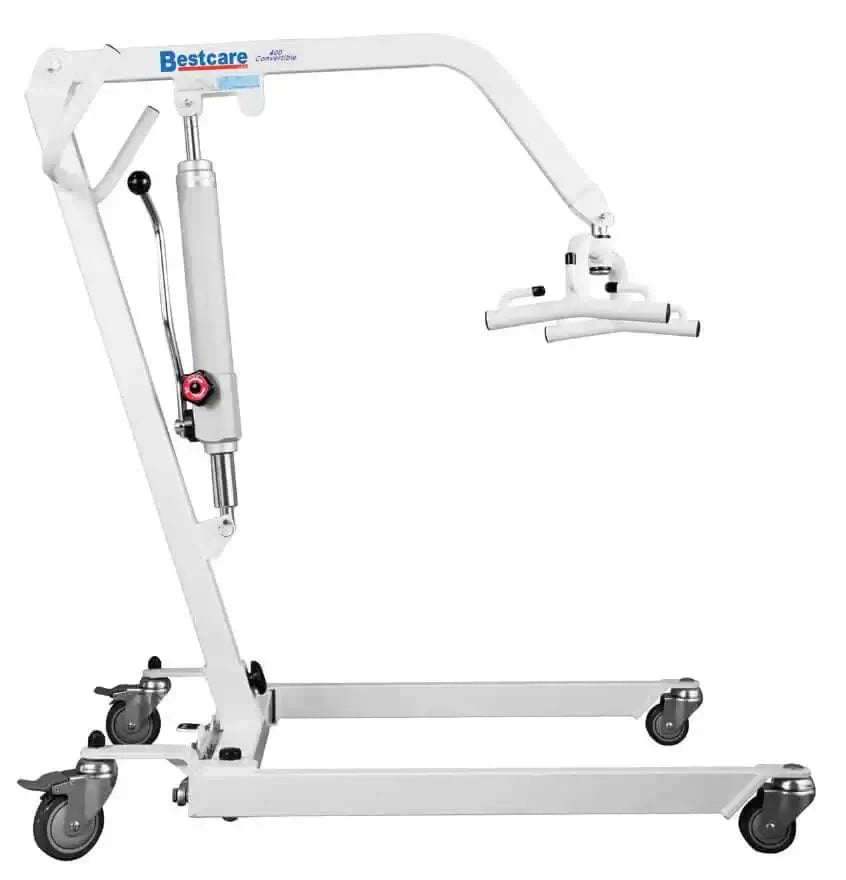 a patient in bed being lifted out by a hoyer lift using a sling and two nurses helping him