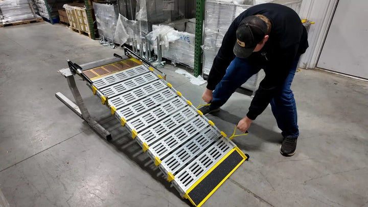 roll-a-ramps assisted bi fold van ramp on reliable ramps being folded up by man using the handles