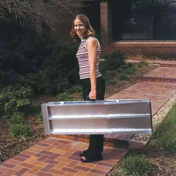 lady holding the PVI Aluminum Single Fold Threshold Ramp like a suitcase