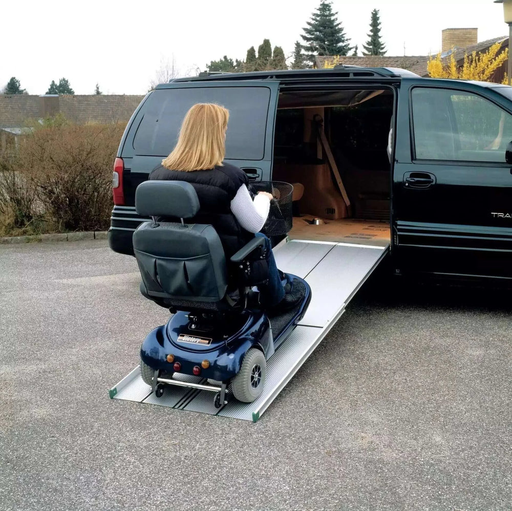 Guldmann - Stepless Telescopic EasyFold Wheelchair Van Ramp being used by lady going up into a vehicle