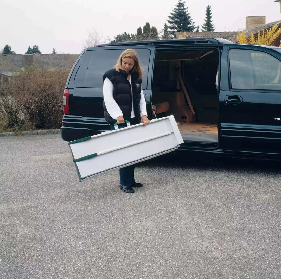Guldmann - Stepless Telescopic EasyFold Wheelchair Van Ramp being held by a lady as its all folded up