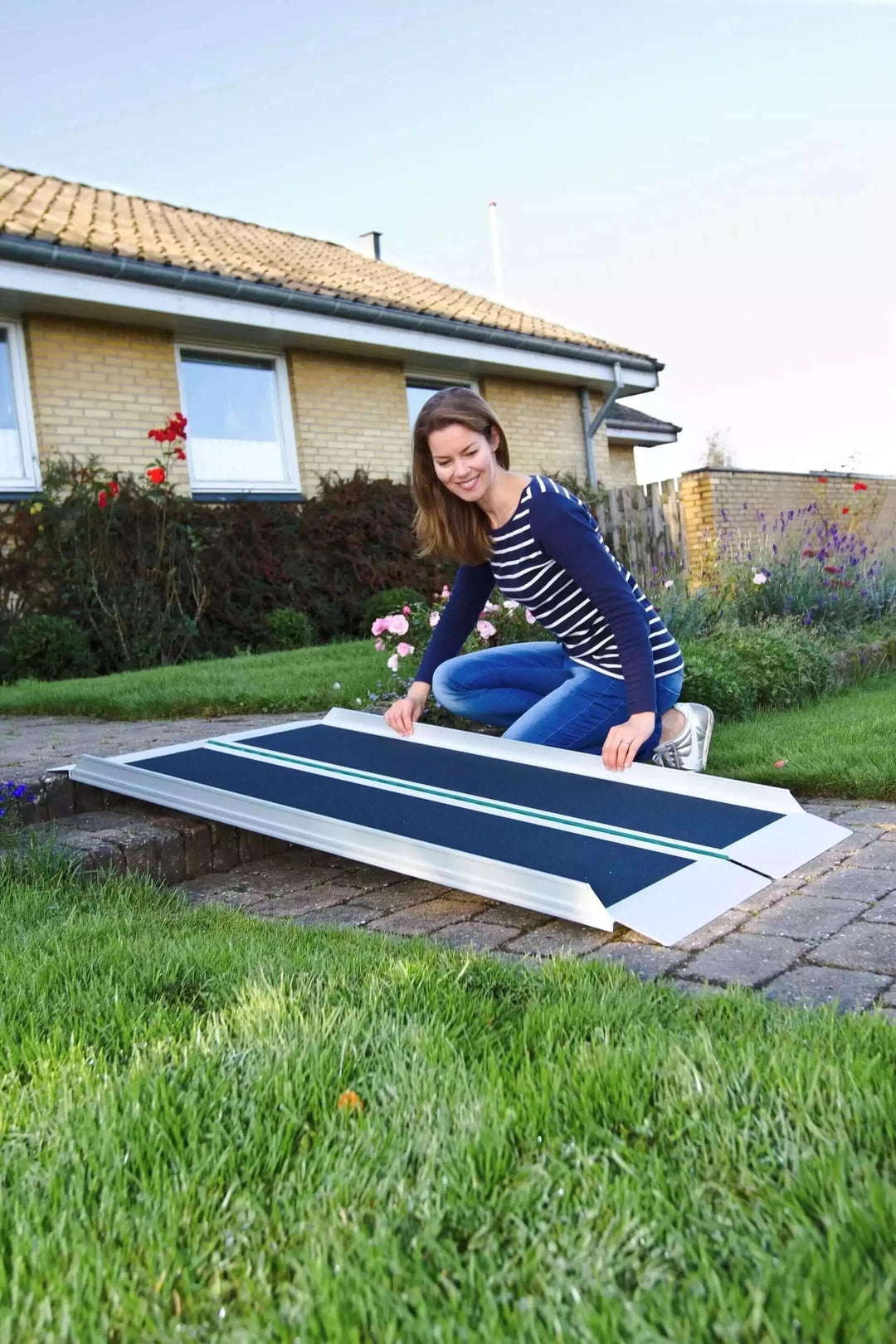 Guldmann - Stepless EasyFold Pro Portable Wheelchair Ramp being laid down by lady to use over curb