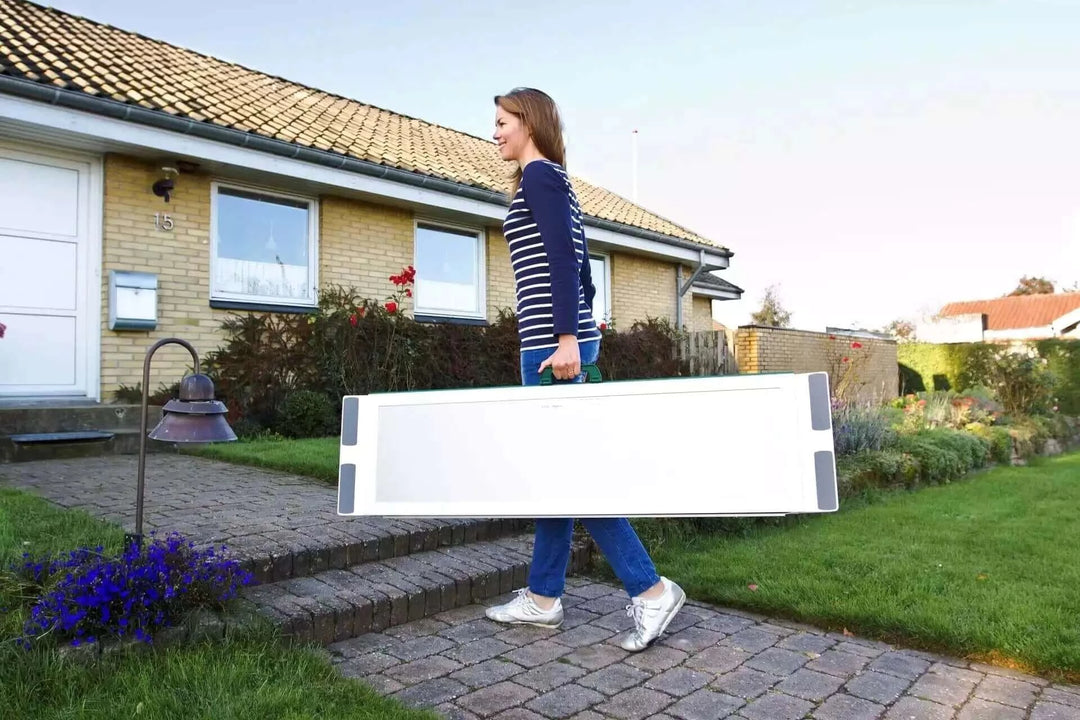 Guldmann - Stepless EasyFold Pro Portable Wheelchair Ramp being carried by user when it's folded up.