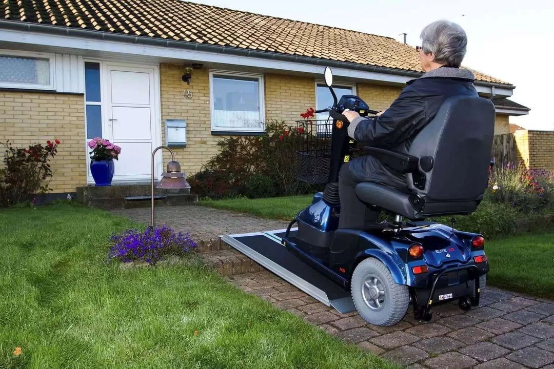 Guldmann - Stepless EasyFold Pro Portable Wheelchair Ramp being used by a handicap person in a motorized scooter