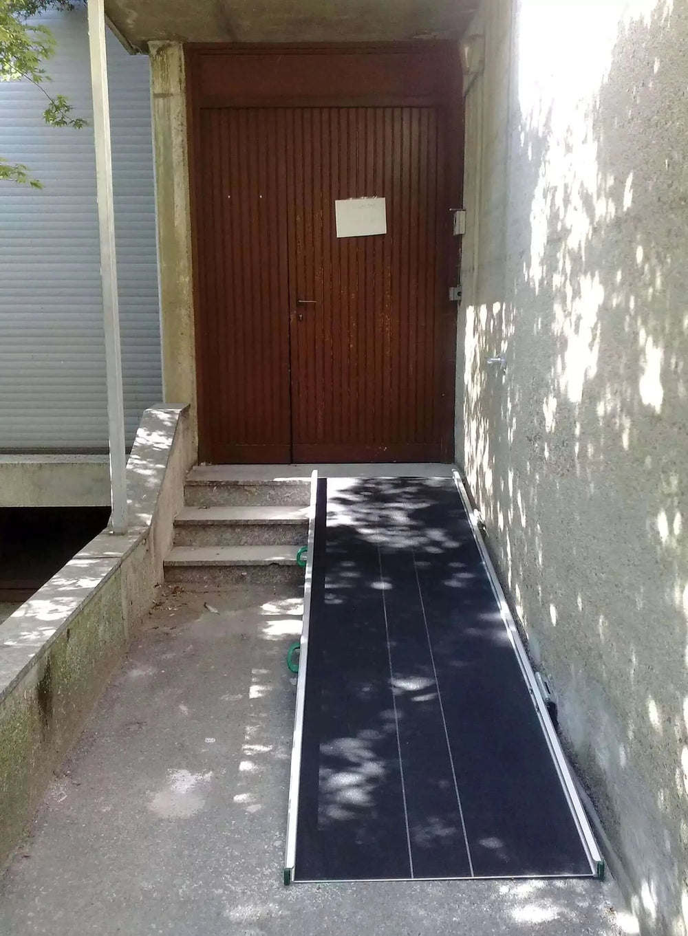 Guldmann - Stepless Wide Folding Portable Wheelchair Ramp setup next to steps at a front home entrance