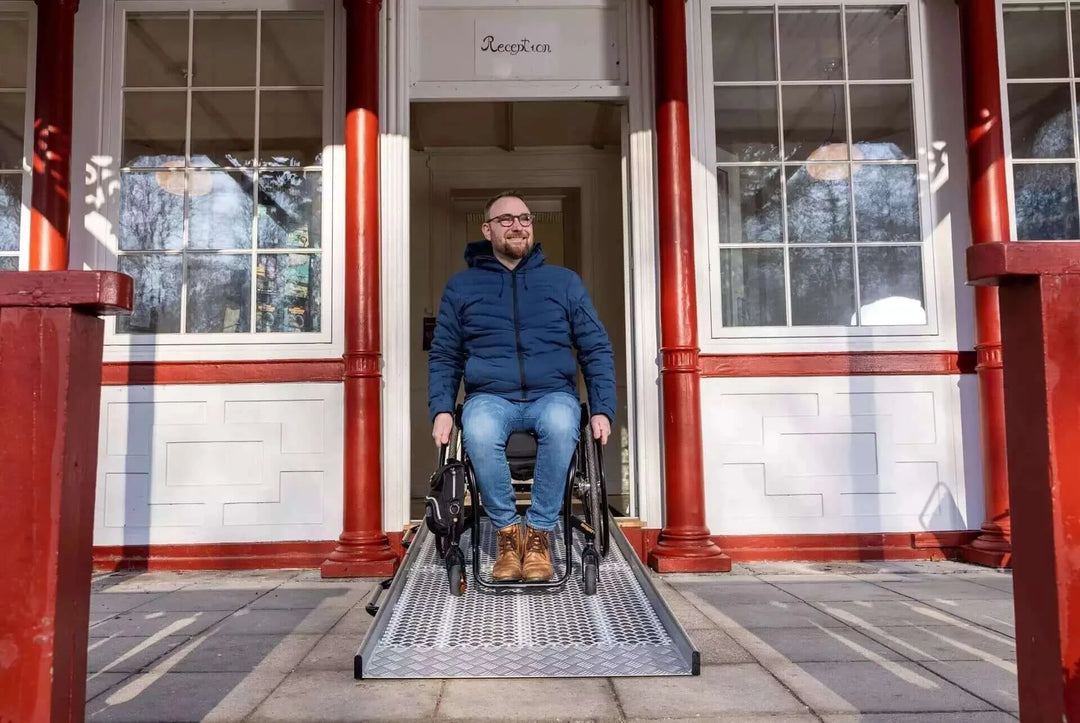 Guldmann - Stepless Wide Folding Pro Portable Wheelchair Ramp used by a patient coming out of a house