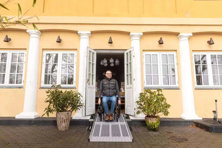 Guldmann - Stepless Wide Folding Pro Portable Wheelchair Ramp used by a patient coming out of a house
