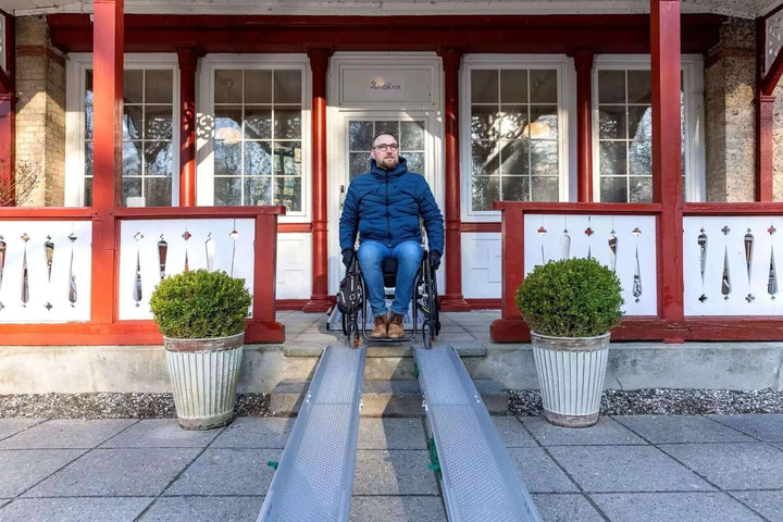Guldmann - Stepless Folding Telescopic Portable Wheelchair Ramp being used outside by handicap patient