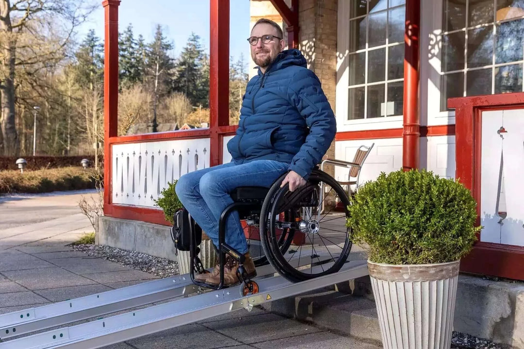Guldmann - Stepless Folding Telescopic Portable Wheelchair Ramp being used by a man coming out of a house