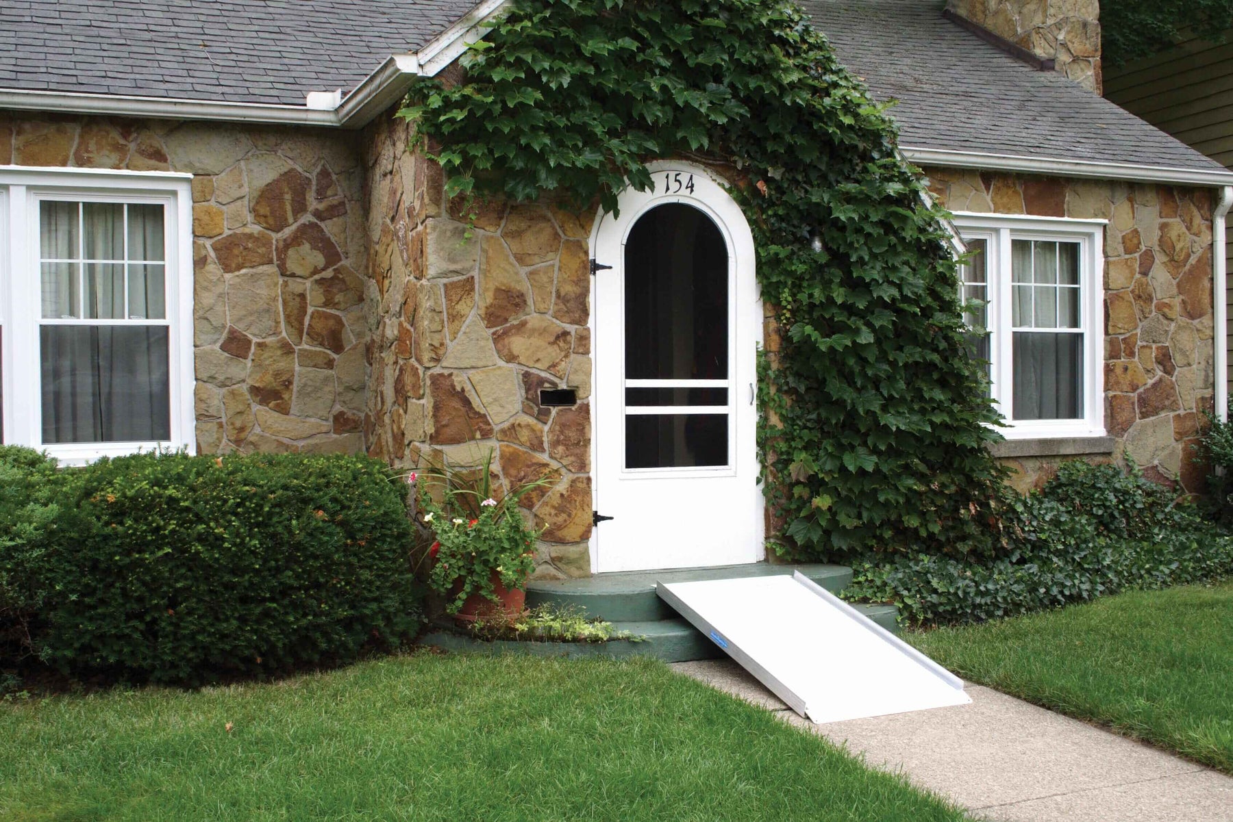 alumiramp solid portable ramp leaned against 2 steps in front of a house