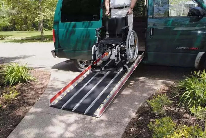 man pushing wheelchair down fiberglass ramp out of astro van
