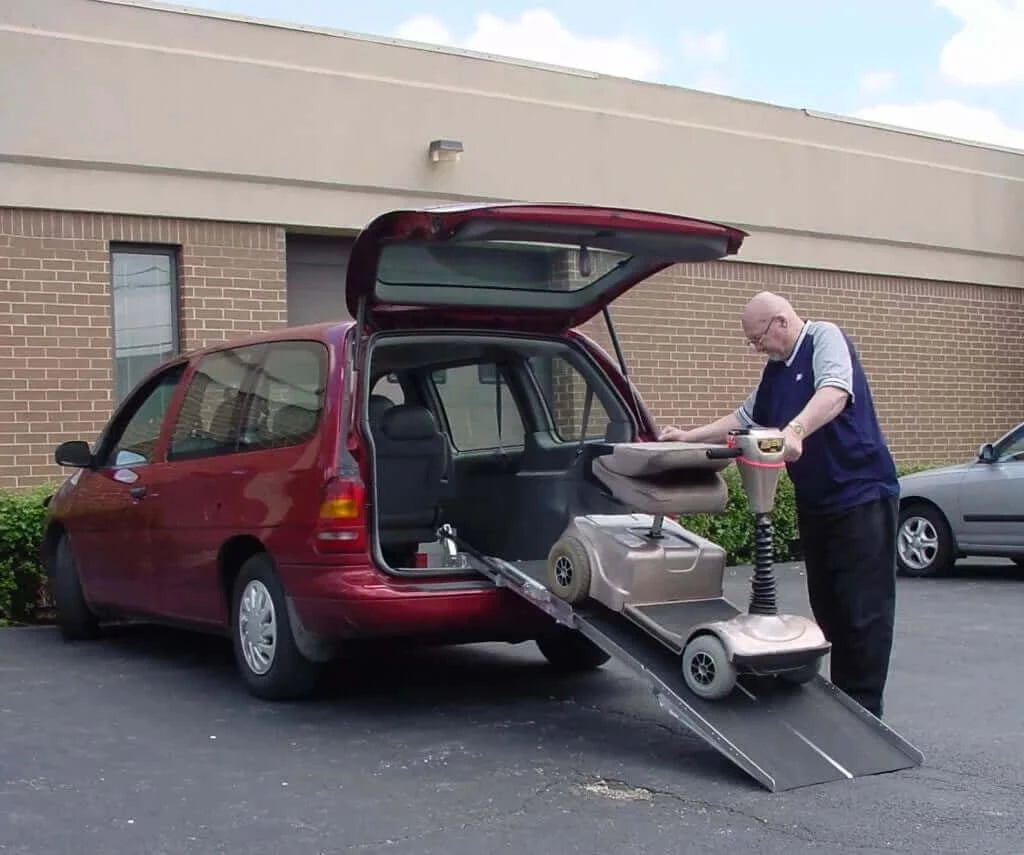 man pushing his motor handicap scooter up a PVI mountable van ramp into his red minivan