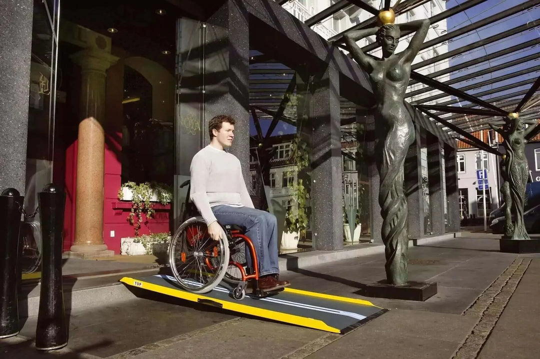 Guldmann - Stepless Single Folding Lite Wheelchair Ramp being used by a man coming down a threshold outside