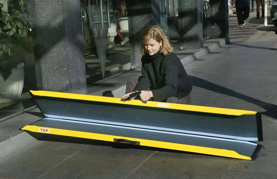 Guldmann - Stepless Single Folding Lite Wheelchair Ramp being held by a user with it folded up