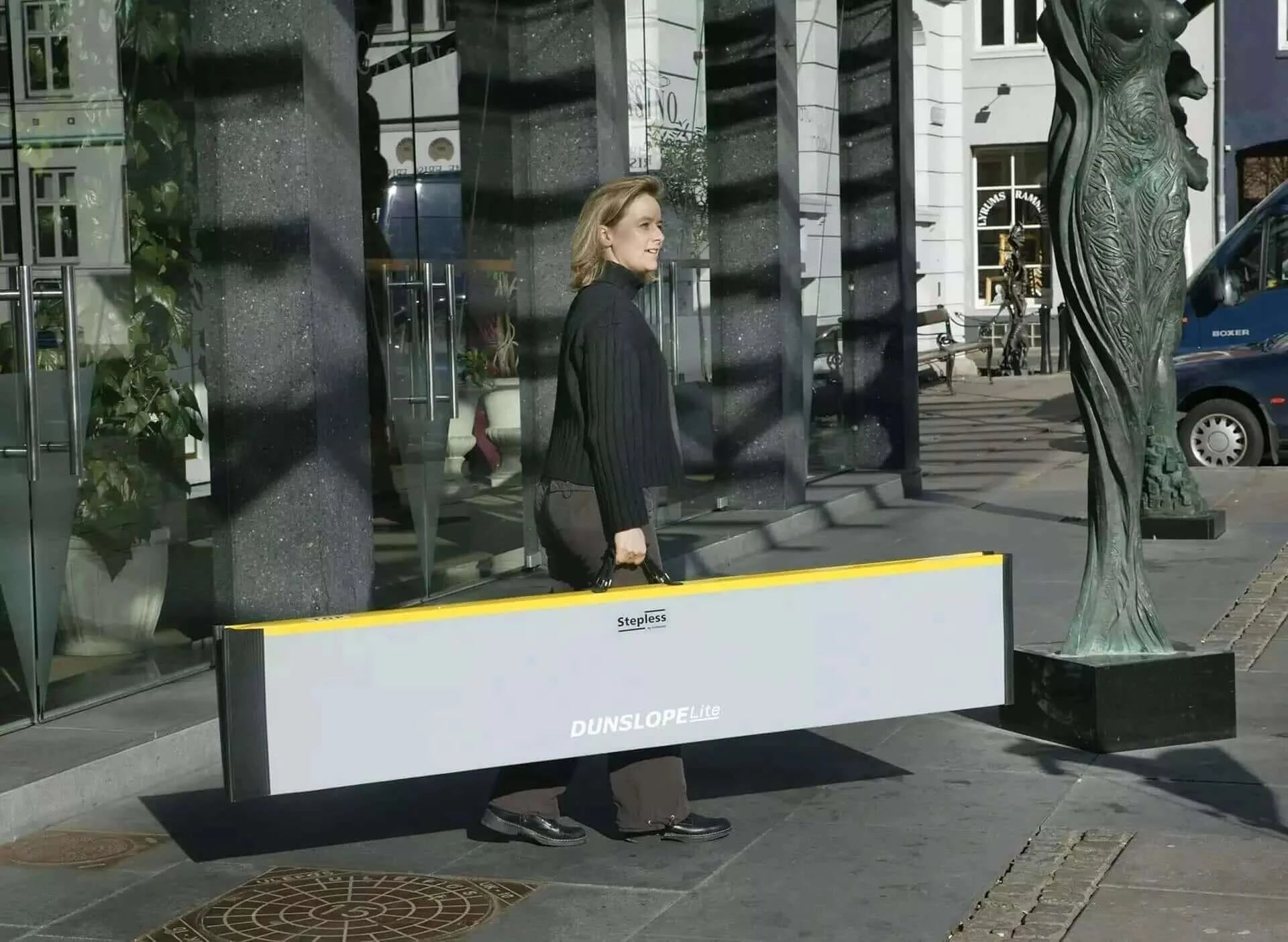 guldmann fiberglass folded suitcase ramp held by a lady outside