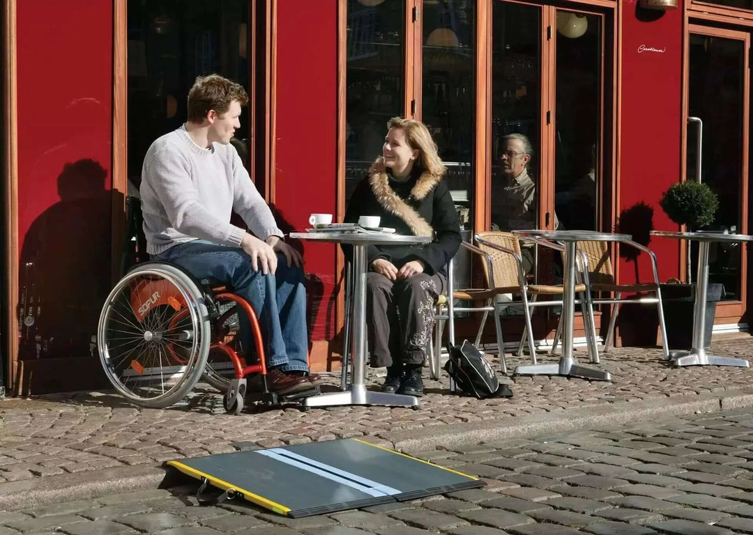 Guldmann - Stepless Single Folding Lite Wheelchair Ramp sitting next to a couple eating laying over a threshold