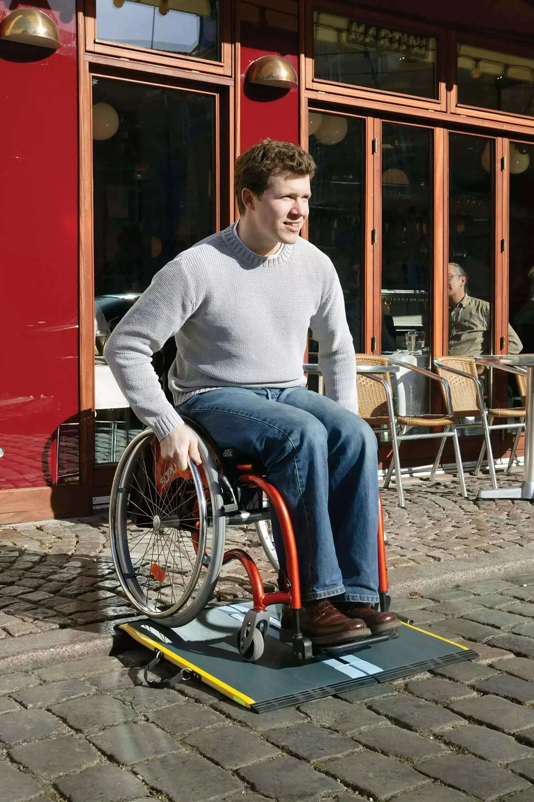 Guldmann - Stepless Multi Folding Lite Wheelchair Ramp andm an using it coming down a small threshold outside
